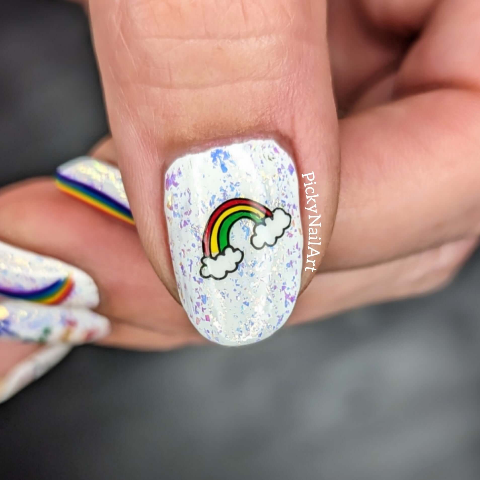 single-manicured-nail-showing-a-nail-art-design-of-a-rainbow-between-two-clouds