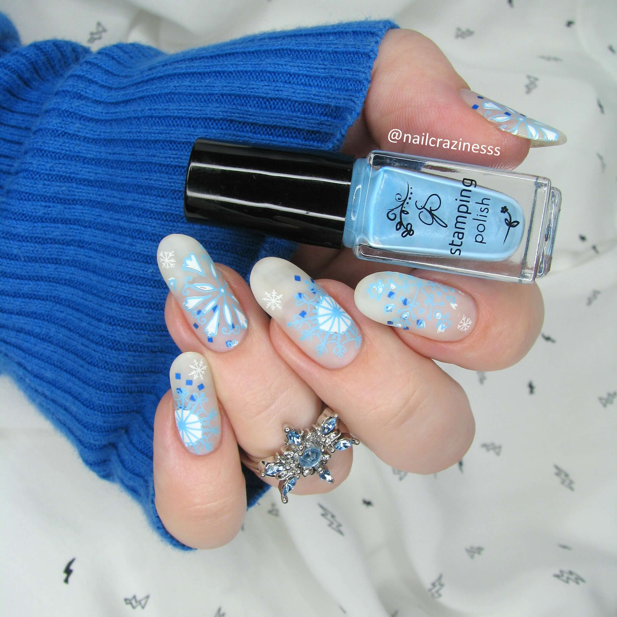 Hand-holding-clear-jelly-stamper-polish-with-beautiful-manicure-showing-snowflake-nail-art-designs