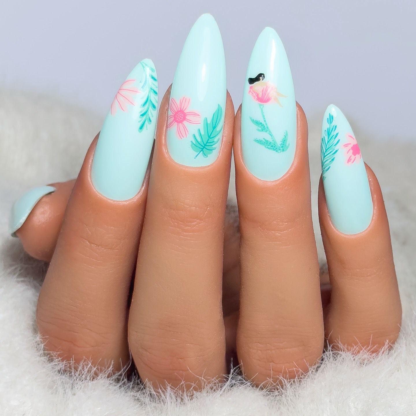 Manicured-hand-showing-delciate-nail-art-designs-of-flowers-in-light-blue-and-pink