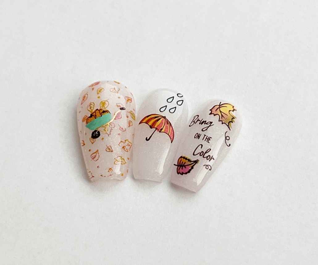 three-nail-tips-showing-colorful-nail-art-designs-of-autumn-leaves-pumpkins-and-words-bring-on-the-color